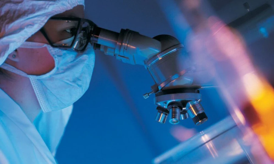 Scientist in laboratory studying bioactive components of deer velvet using advanced microscope, demonstrating precision and scientific rigor in researching regenerative properties