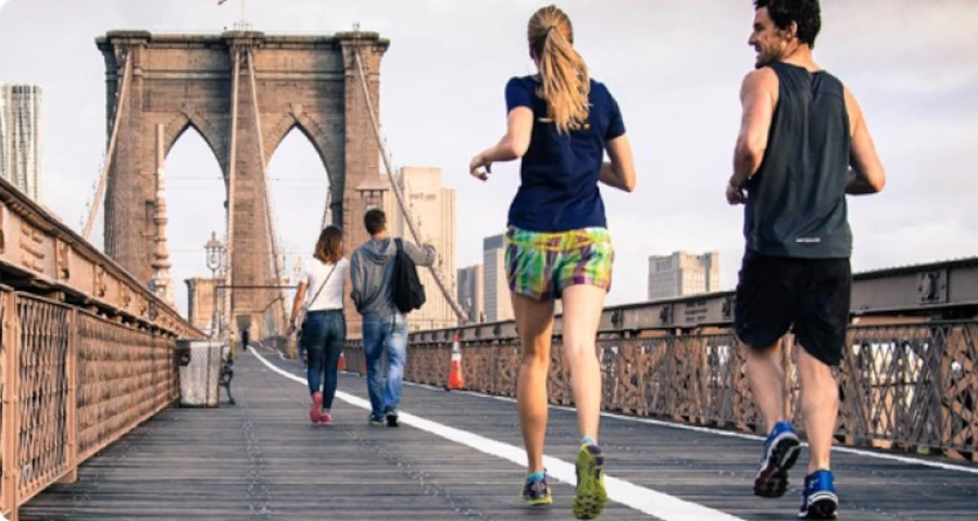 Young people jogging across Brooklyn Bridge, demonstrating active lifestyle and physical fitness that can be maintained at any age through the natural regenerative properties of deer velvet