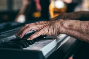 Senior's hands playing piano, demonstrating preservation of fine motor skills and joint flexibility in older age that can be supported by the natural regenerative potential of deer velvet